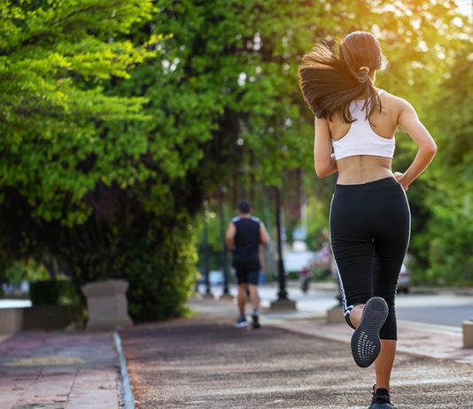 Jovem mulher está correndo numa pista de cooper para manter a saúde. É um dos exercícios físicos bem fáceis.