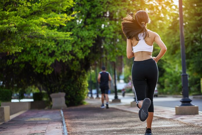 Jovem mulher está correndo numa pista de cooper para manter a saúde. É um dos exercícios físicos bem fáceis.