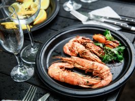 Imagem de um prato com camarão fresco, tendo legumes como acompanhamento.