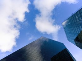Dois imponentes e sofisticados prédios com fachada de vidro se mantêm lado a lado, como se estivessem conversando lá nas alturas, com o topo tão perto do céu. A ideia é fazer uma analogia com os poderosos bancos, que se entendem entre eles, longe do que acontece na rua com as pessoas. Os bancos praticam elevada taxa de juros.