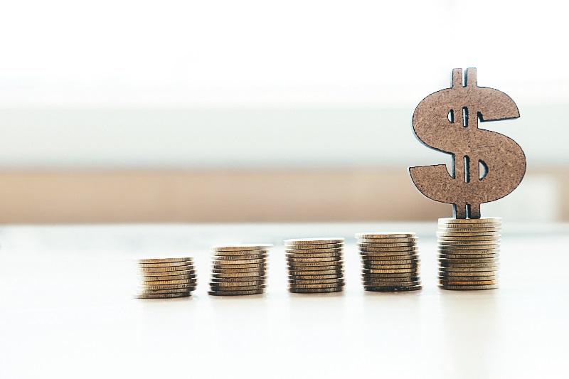 Pilhas de moedas, com um cifrão em cima mostra que é preciso guardar dinheiro.