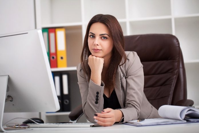 Mulher executiva está em sua mesa de trabalho e olha um blog.